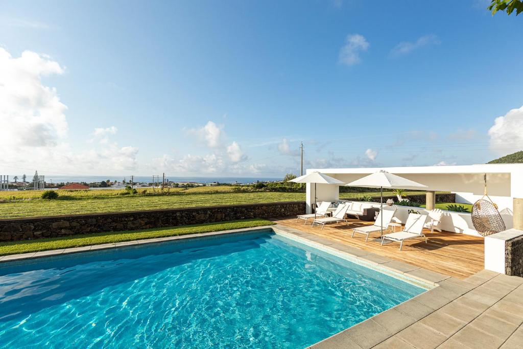 a swimming pool with chairs and a pavilion at Casa do Pico Arde in Ribeira Grande