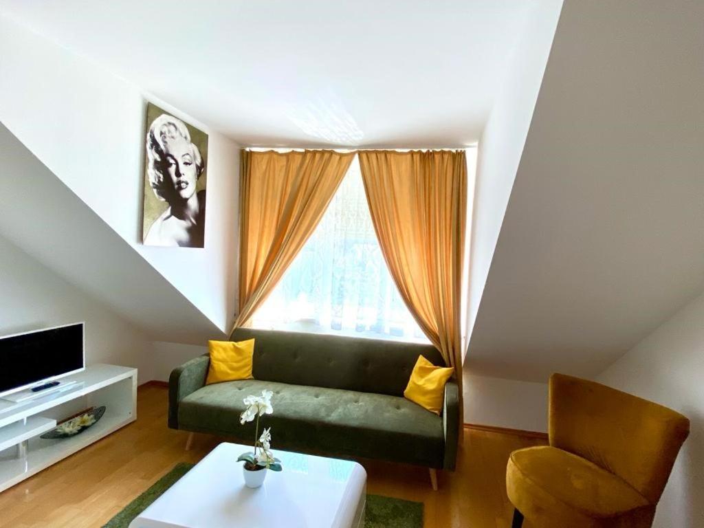 a living room with a green couch and a window at Cosy apartment in central location in Vienna