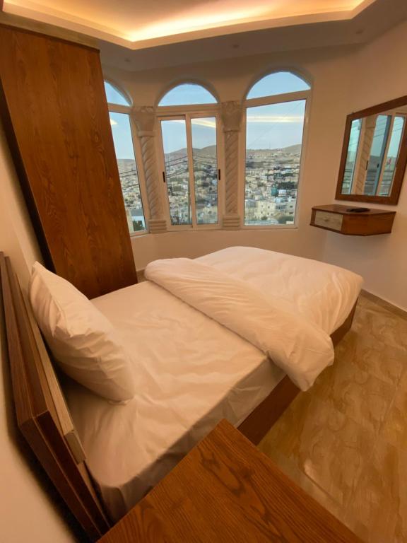 Cama grande en habitación con ventanas en Petra Family Hotel, en Wadi Musa