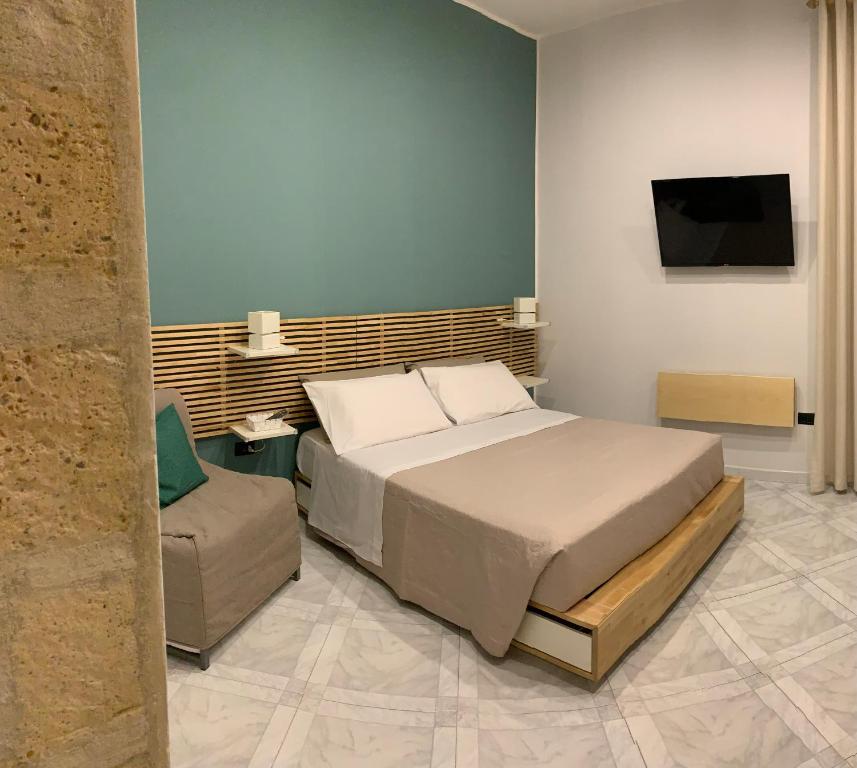 una camera con letto, sedia e televisore di IlGirasoleApartment a Napoli
