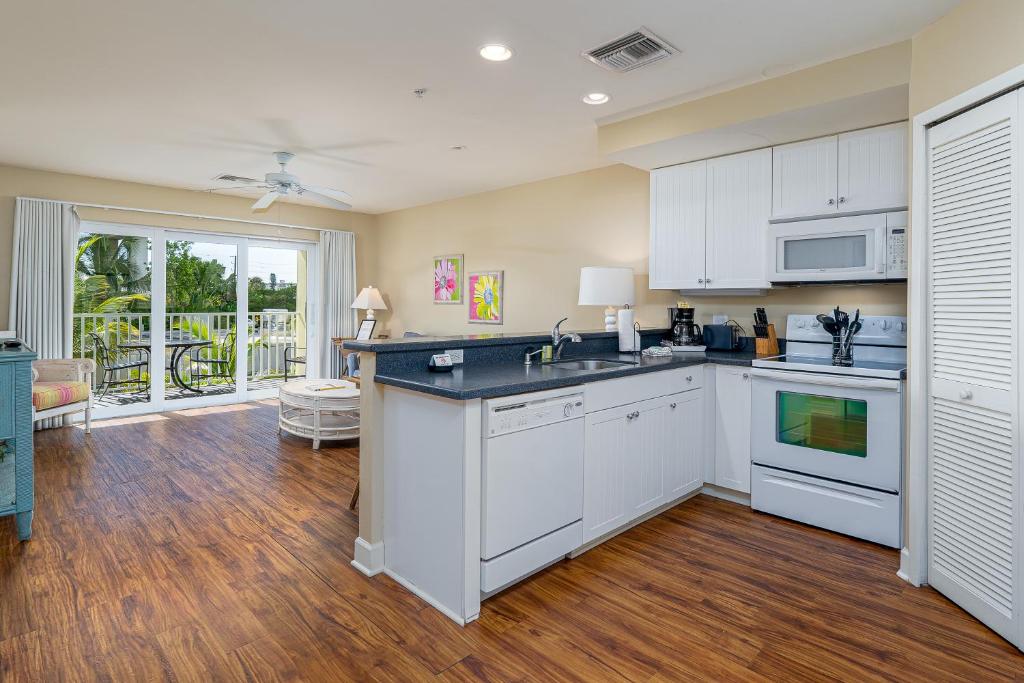 a kitchen with white cabinets and a hardwood floor at Harbour House at the Inn 214 in Fort Myers Beach
