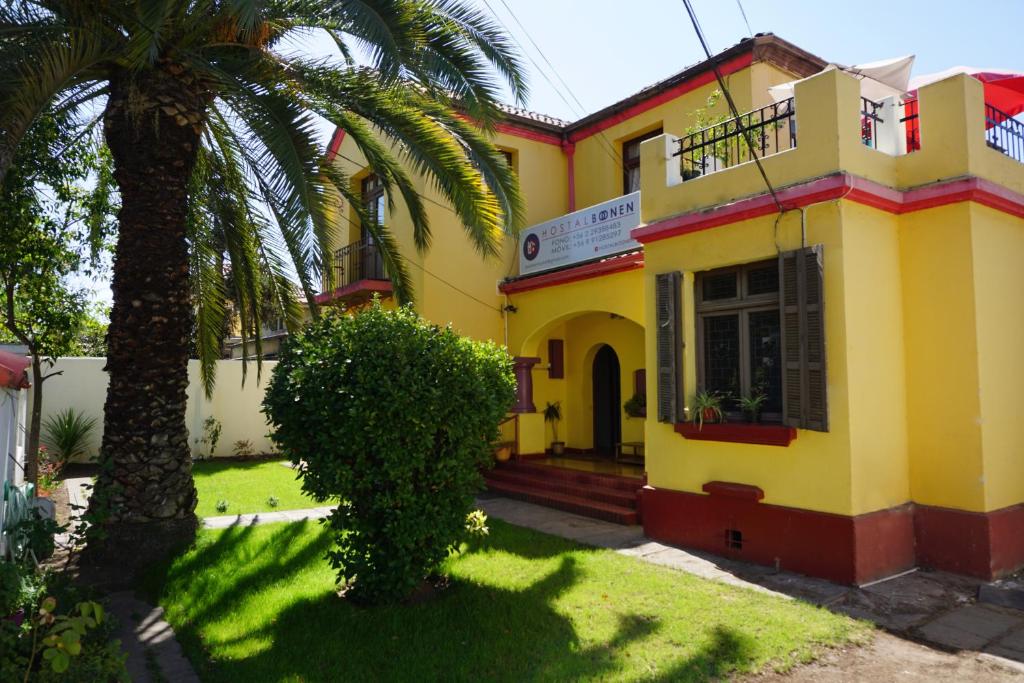 un edificio amarillo con una palmera delante en Hostal Boonen, en Santiago