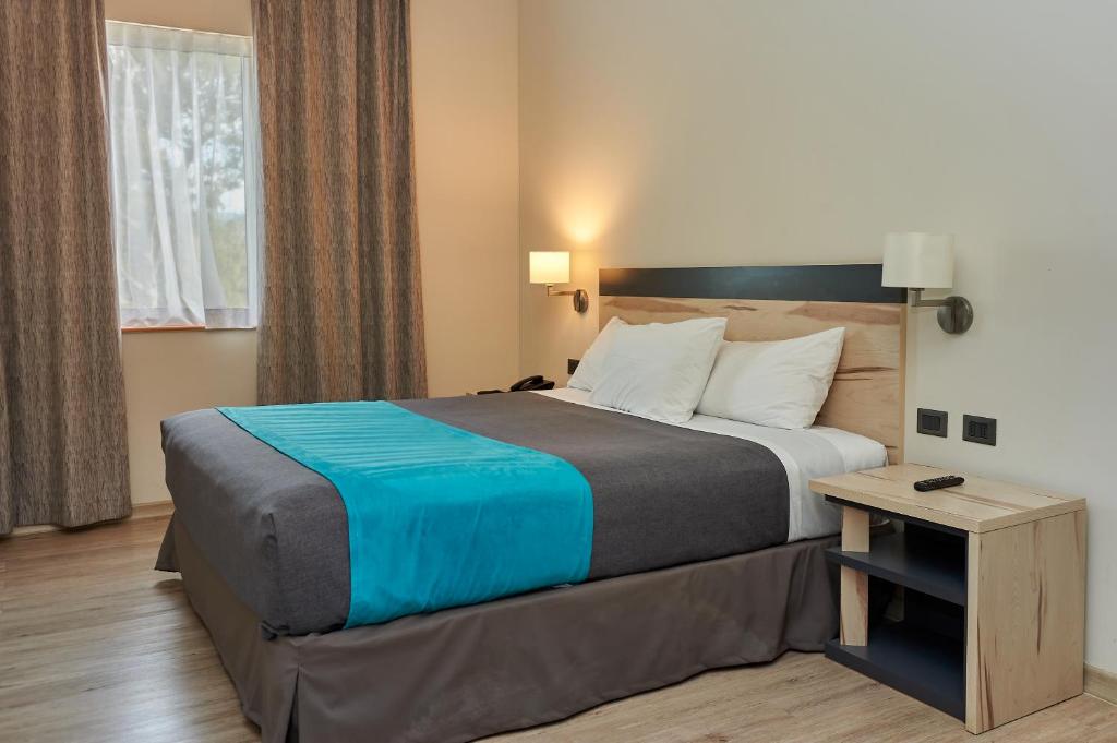 a hotel room with a large bed and a table at Hotel Diego de Almagro Talca Express in Talca