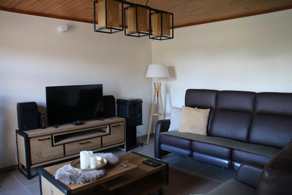 un soggiorno con divano e TV di Charmante maison de campagne "Chemin Saint-Roch" 