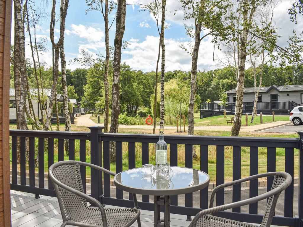a table and chairs on a balcony with trees at Deer Glade Lodge in Landford