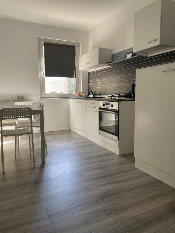 a kitchen with white cabinets and a table with a chair at estrella24 LIVING ROOMS London in Herne