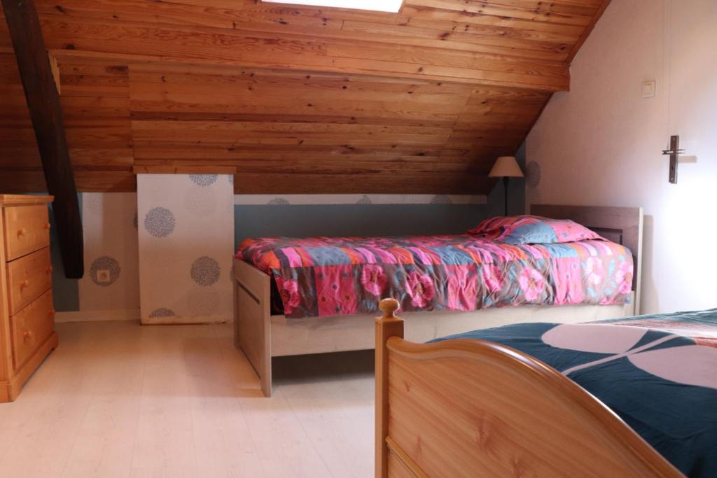 1 dormitorio con 2 camas y techo de madera en Gite Clé Vacances Courchaton, 