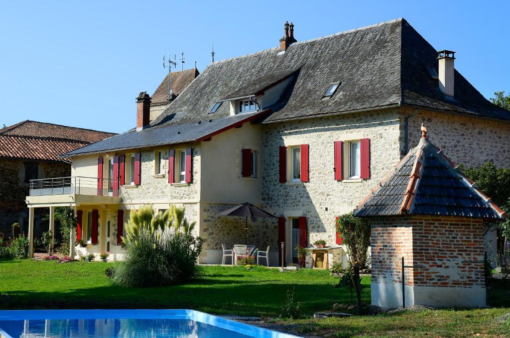 a large house with red windows and a swimming pool at Au Clos du Célé in Bagnac