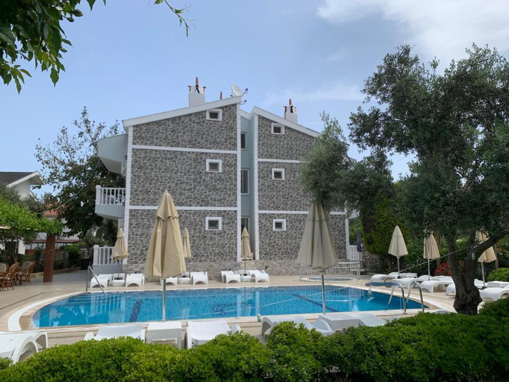 un hotel con piscina con ombrelloni di Gökmen Apartments a Turunç
