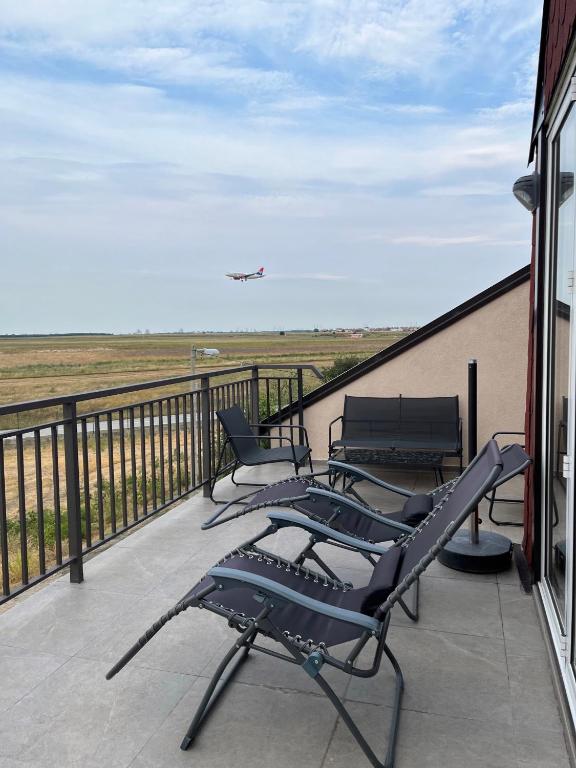 a balcony with chairs and an airplane flying in the sky at 5 min to Airport Gate 25 - Free Parking -Easy Check-in in Ledine