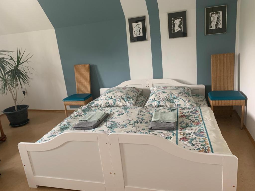 a white bed in a room with two chairs at Ruhiges Zimmer nahe Therme & Kurpark in Bad Steben