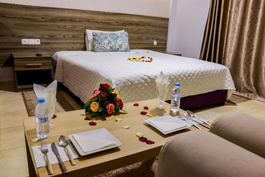 Cette chambre comprend un lit et une table fleurie. dans l'établissement HOTEL BORJ SAFAE LAAYOUNE, à Laâyoune