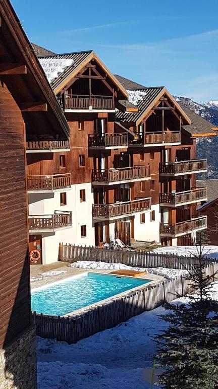 un bâtiment avec une piscine devant dans l'établissement Appartement 4/6 personnes, au pied des pistes, à Puy-Saint-Vincent