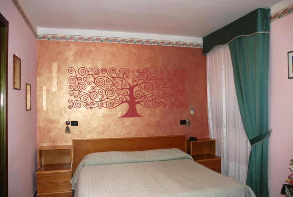 a bedroom with a tree mural on the wall at Hotel Grillo Verde in Torre Annunziata