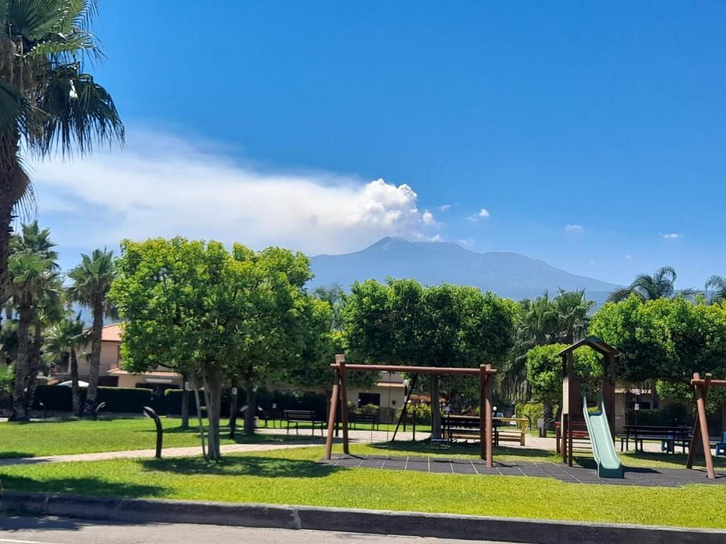 un parc avec une aire de jeux avec des montagnes en arrière-plan dans l'établissement Sun House Sicily, à Mascali