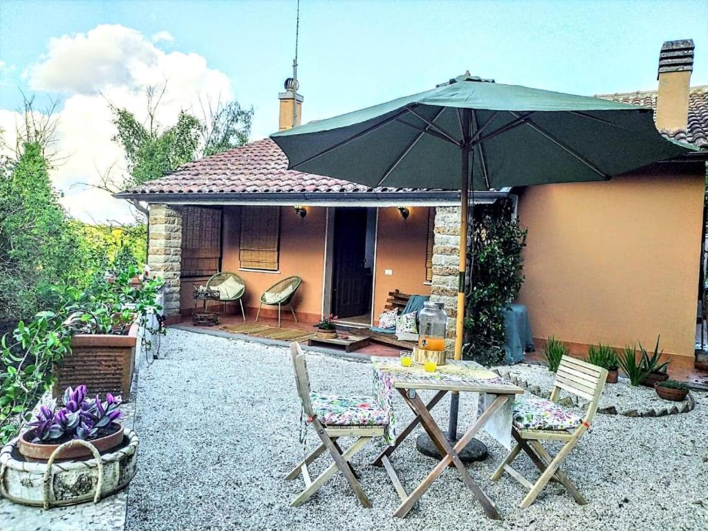 um pátio com uma mesa, cadeiras e um guarda-sol em roncio' cottage em Ronciglione