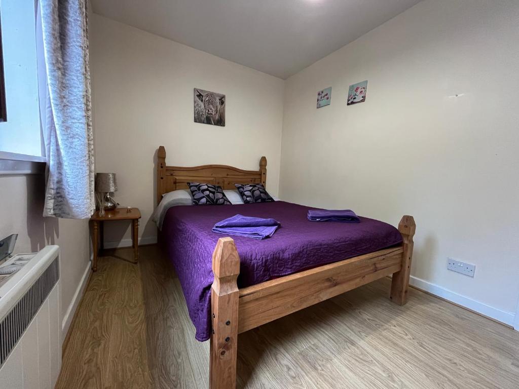a bedroom with a wooden bed with purple sheets at River View Apartment in Elgin