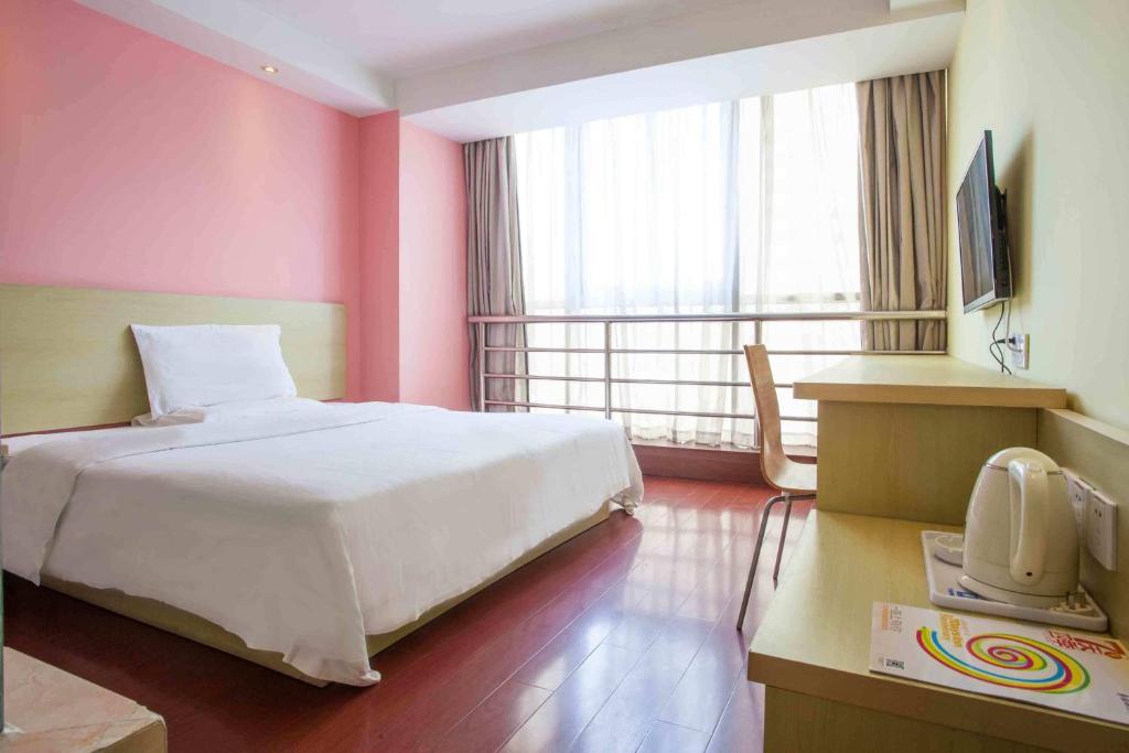 重慶市にある7Days Inn Chongqing Jiangbei Airport Industrial Parkのピンクの壁のベッドルーム1室(白いベッド1台付)