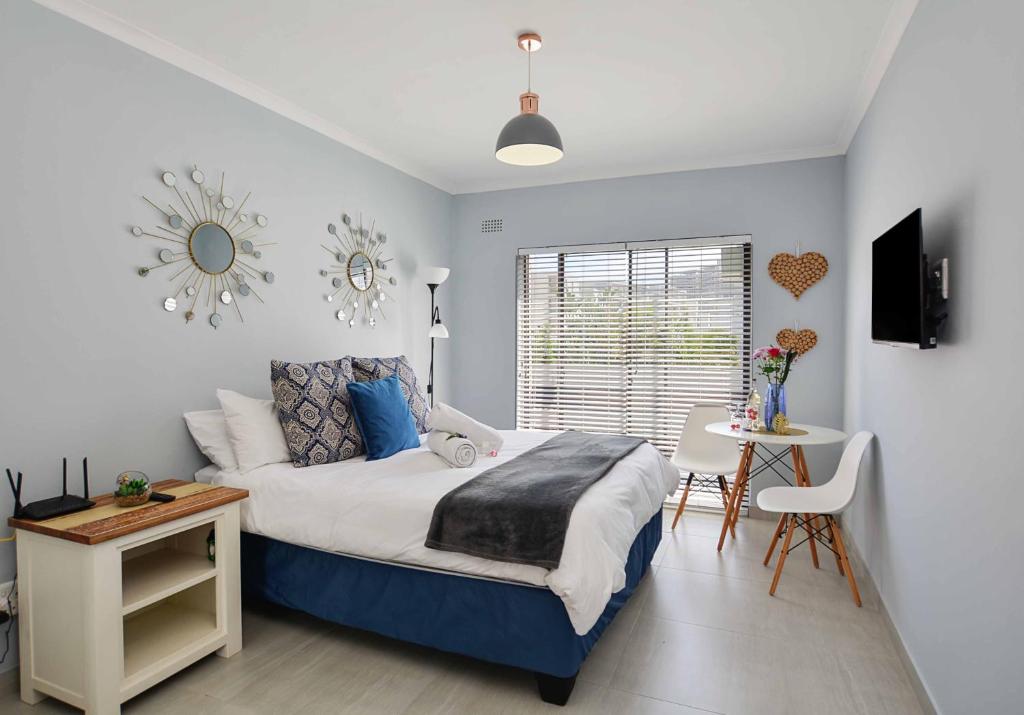 a bedroom with a bed and a table and a window at Sea Breeze Apartments in Bloubergstrand
