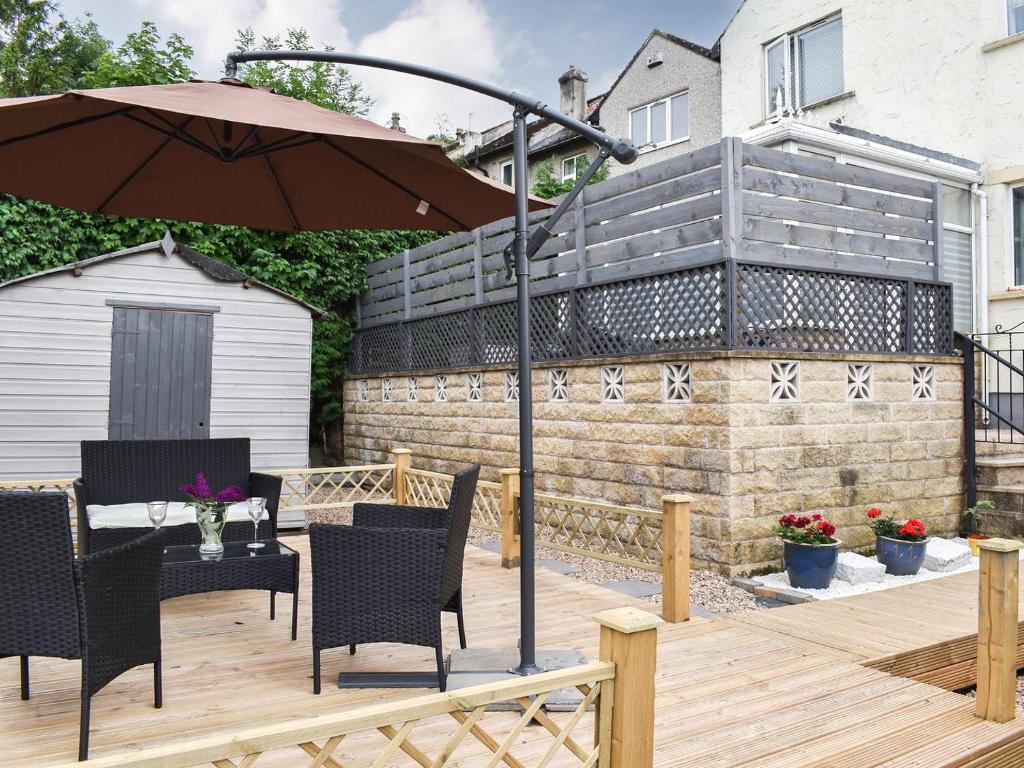 a patio with an umbrella and chairs on a wooden deck at Huddersfield House, Wood View in Huddersfield