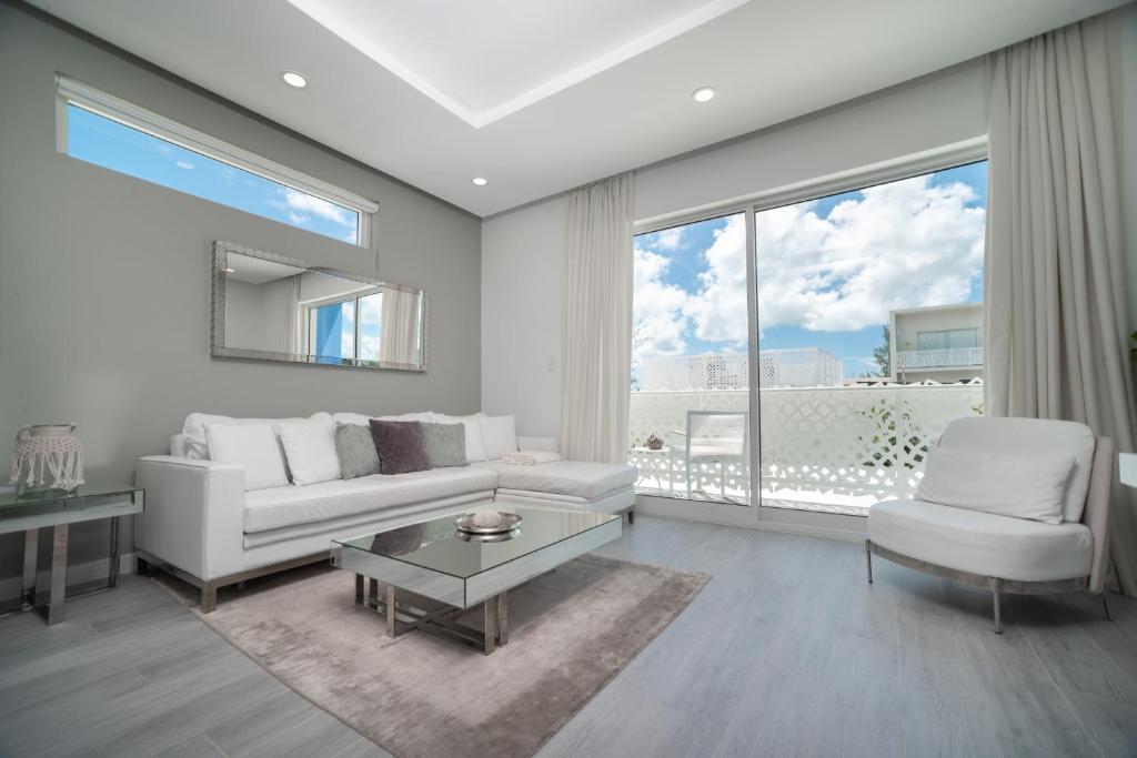 a living room with white furniture and a large window at Luxury 1 bed apartment near Seven Mile Beach at The Grove - Villa Deluxe in Upper Land