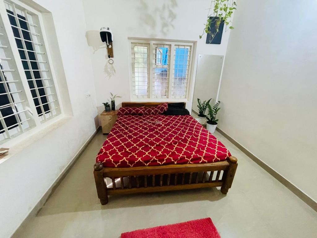 a bedroom with a bed with a red comforter at Wayanad Biriyomz Residency, Kalpatta, Low Cost Rooms and Deluxe Apartment in Kalpetta