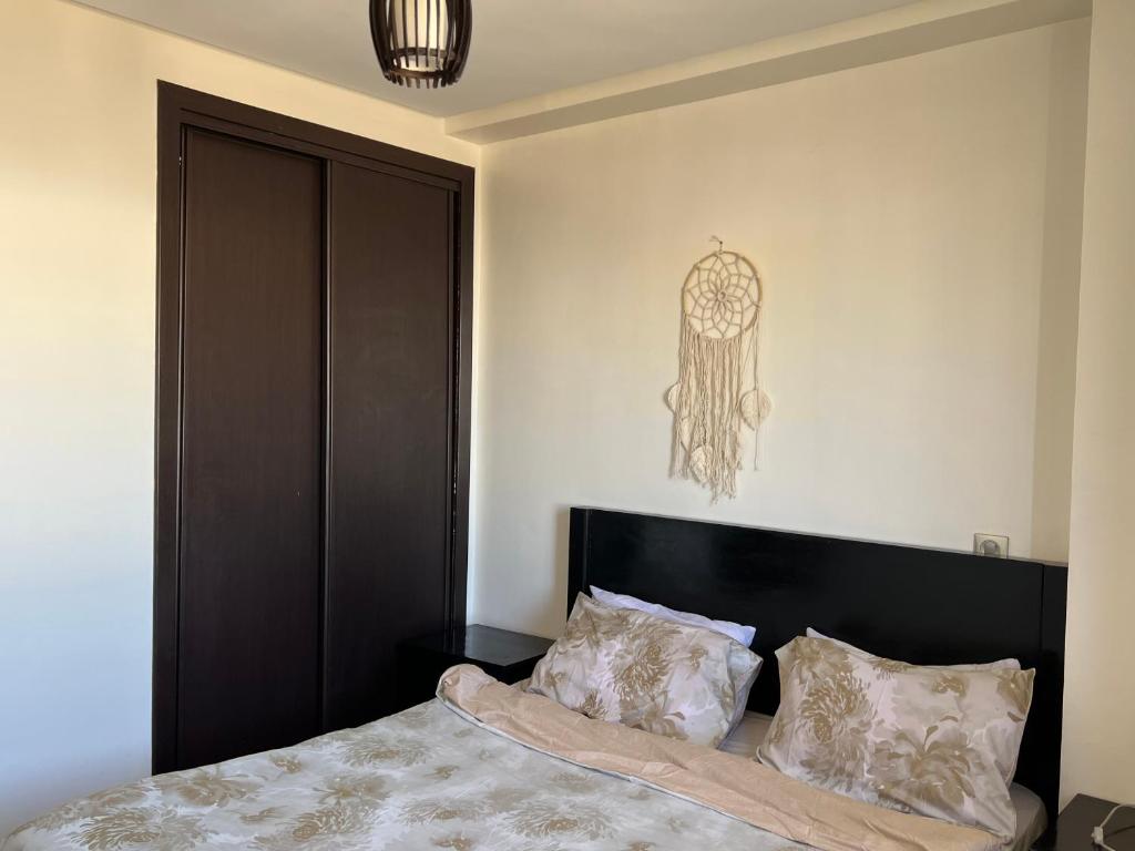 a bedroom with a bed with a black headboard and pillows at nice little apartment with swimming pool in Agadir