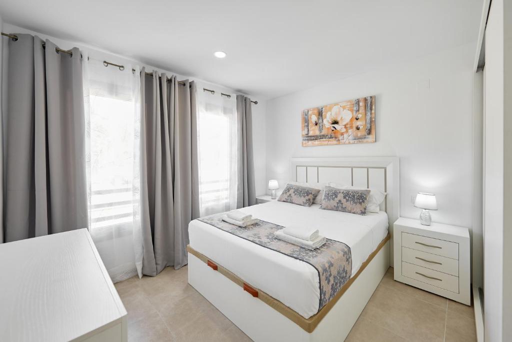 a white bedroom with a bed and a window at Sonrisa Deluxe Apartments, Levante in Benidorm