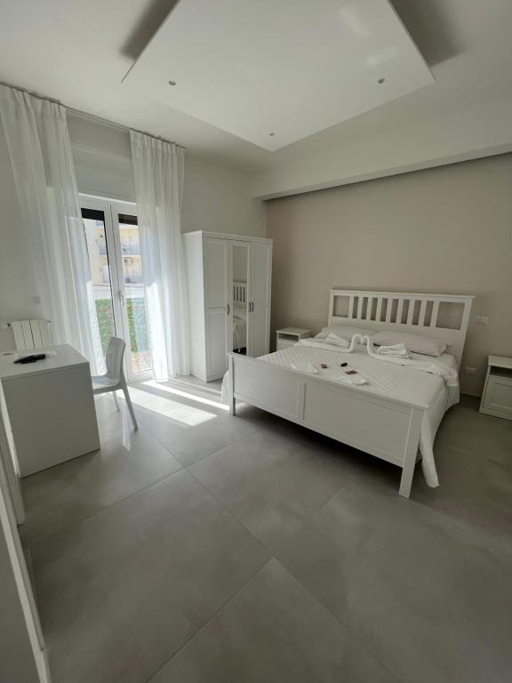 a white bedroom with a bed and a table and chairs at Campione 5 in Bari