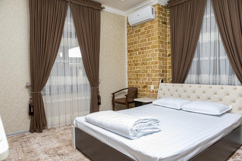 a bedroom with a white bed with a brick wall at AHMAD HOTEL in Samarkand