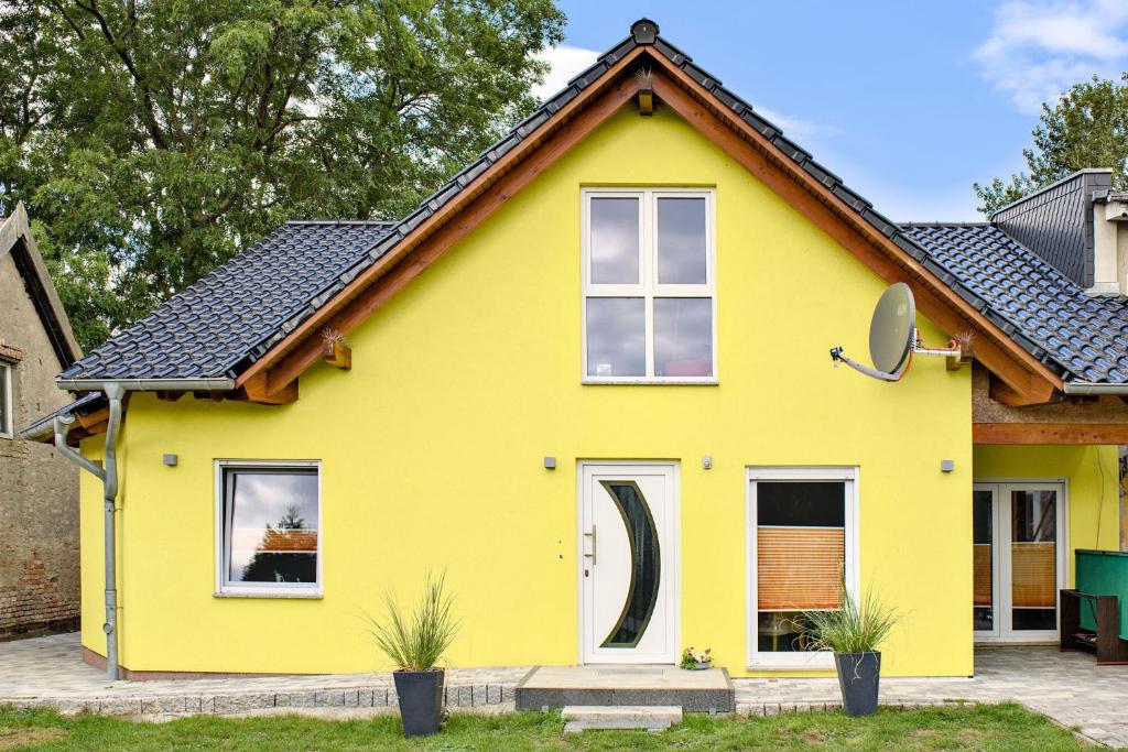 una casa amarilla con techo negro en Fewo Usedom Peene Idyll, en Wolgast