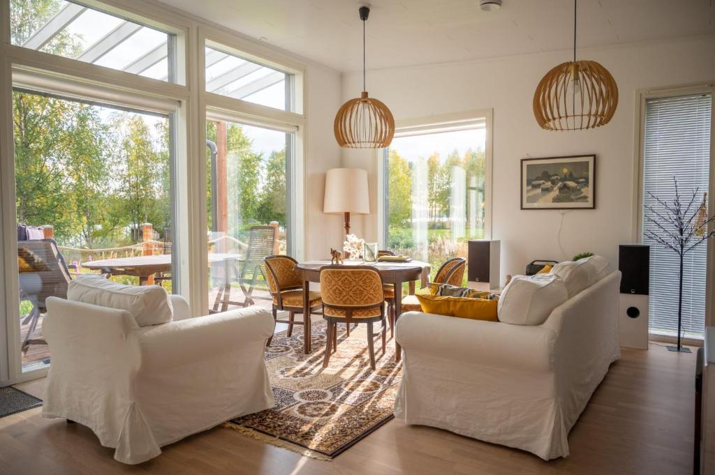 uma sala de estar com cadeiras brancas e uma mesa em Villa Puistola & sauna, near Santa's Village em Rovaniemi