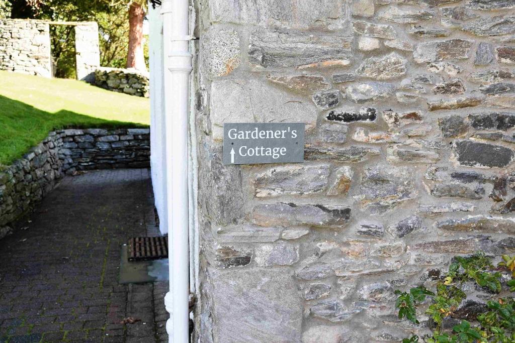 un cartello sul lato di un muro di pietra di The Gardeners Cottage a Pitlochry