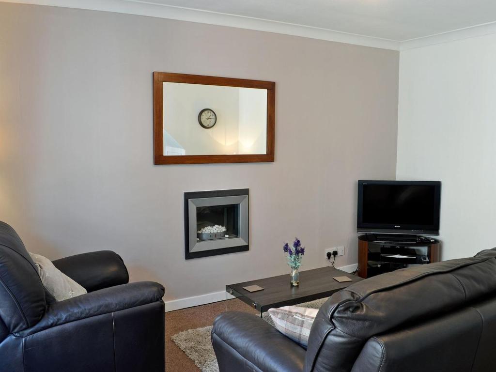 a living room with a couch and a table and a mirror at Summerlea Cottage in Moffat