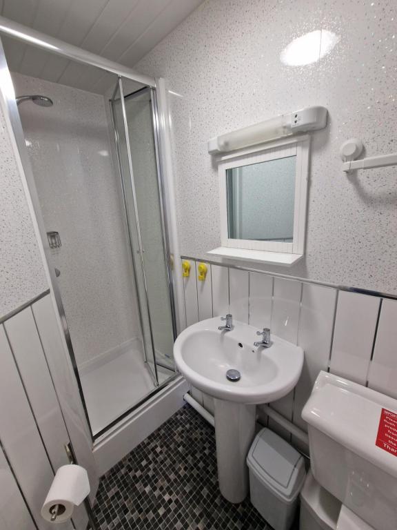 uma casa de banho com um lavatório, um chuveiro e um WC. em Breeze B&B em Llandudno