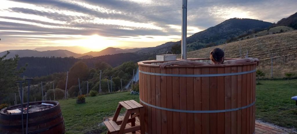 a person sitting in a hot tub with the sunset at Vikendica RANKOVIĆI in Mokra Gora