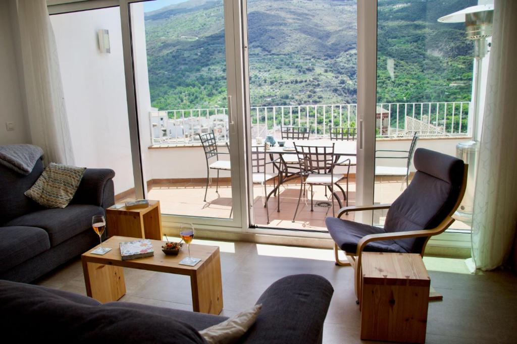 Una sala de estar con un sofá y sillas y una ventana grande. en Guejar Sierra House with Spectacular Views, en Güéjar-Sierra