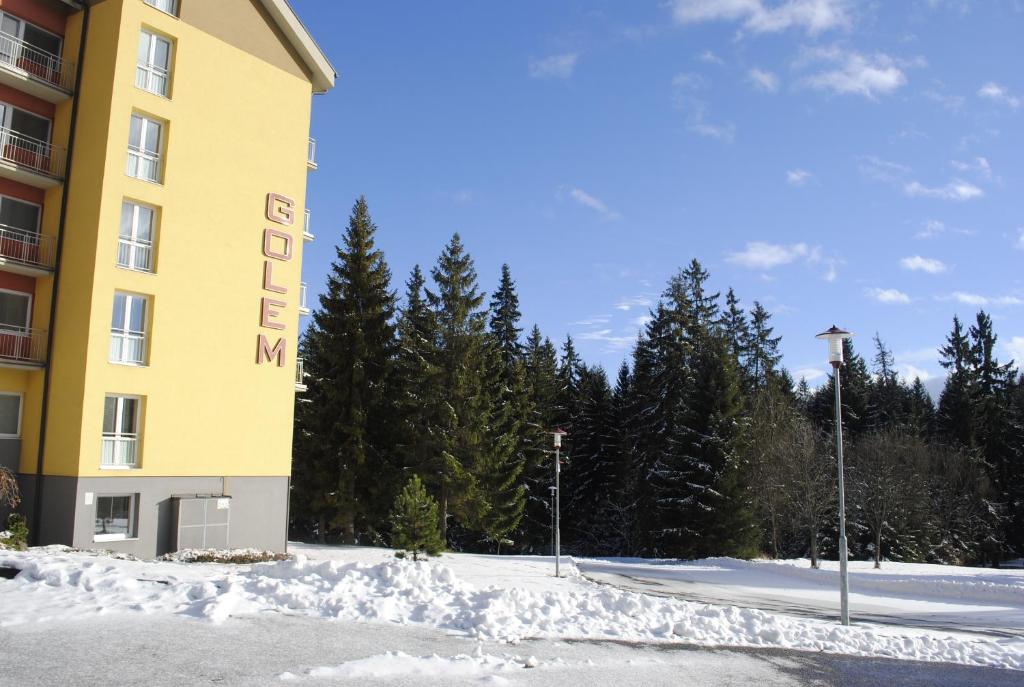 a yellow building with a sign on it in the snow at Golem Tatranská Štrba in Tatranska Strba