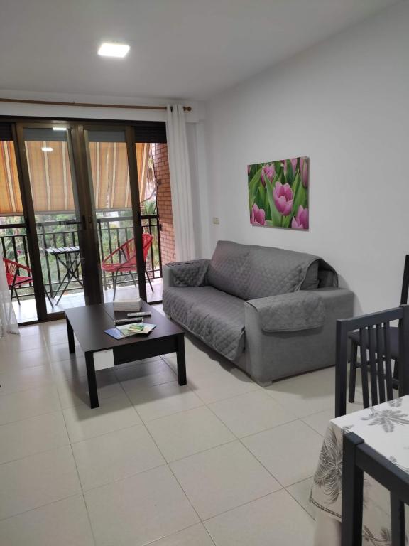 ein Wohnzimmer mit einem Sofa und einem Tisch in der Unterkunft Apartamento con balcón cerca del centro in Castellón de la Plana