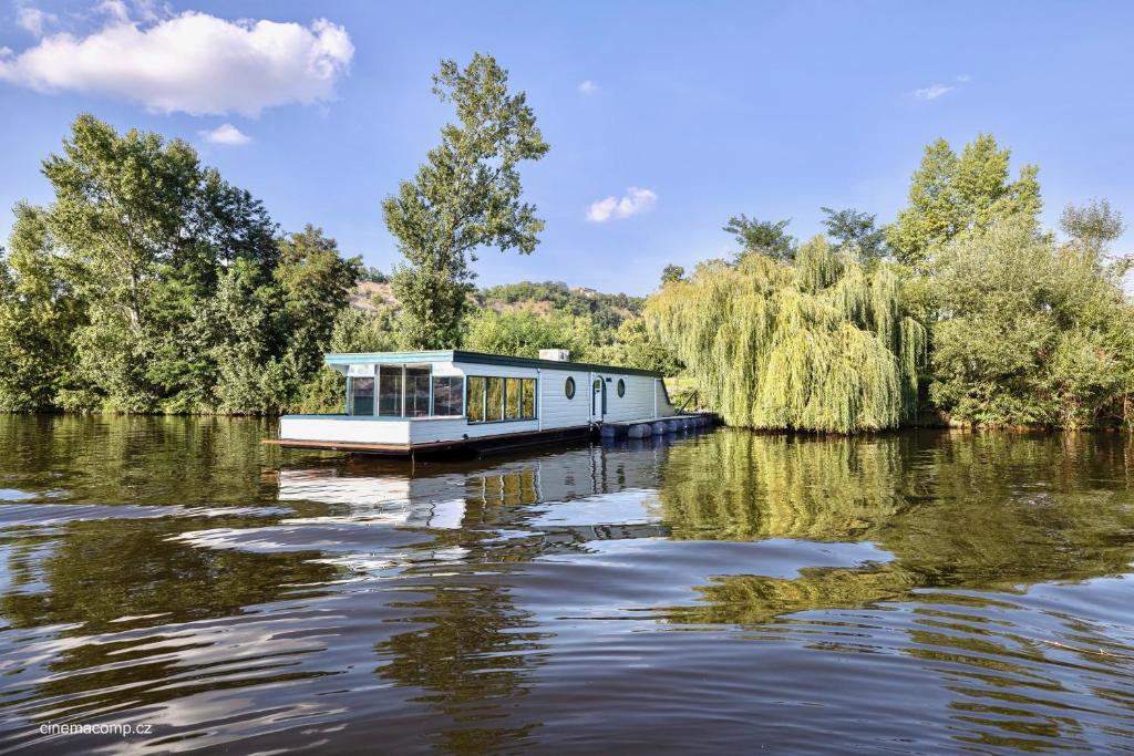 un barco en un río con árboles en el fondo en Houseboat - best place in Prague en Praga