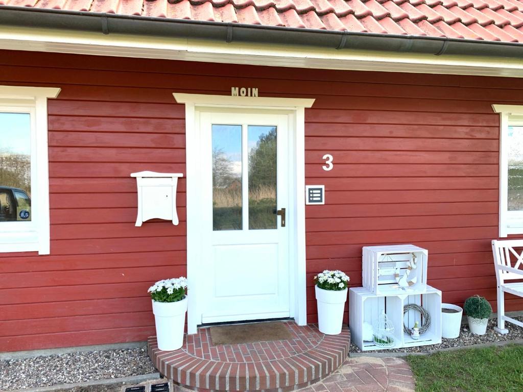 una casa roja con una puerta blanca en Hedwig meine Perle, en Hedwigenkoog