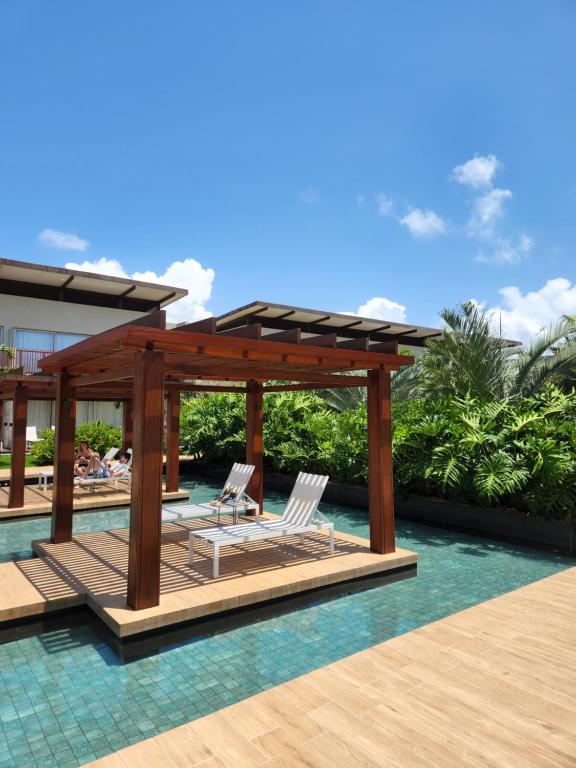 a swimming pool with a pergola and two chairs on a wooden deck at Flat Île de Pipa Resort - Centro in Pipa