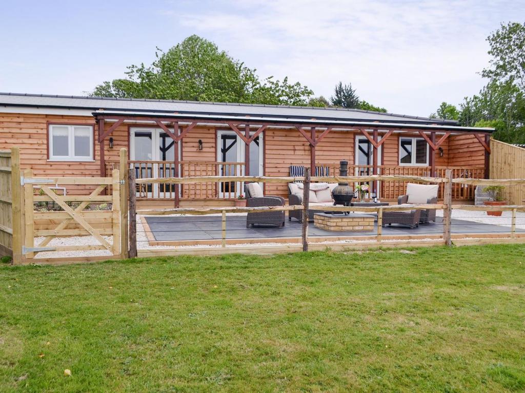 a modular log cabin with a deck and lawn at Cedar Lodge in Herstmonceux