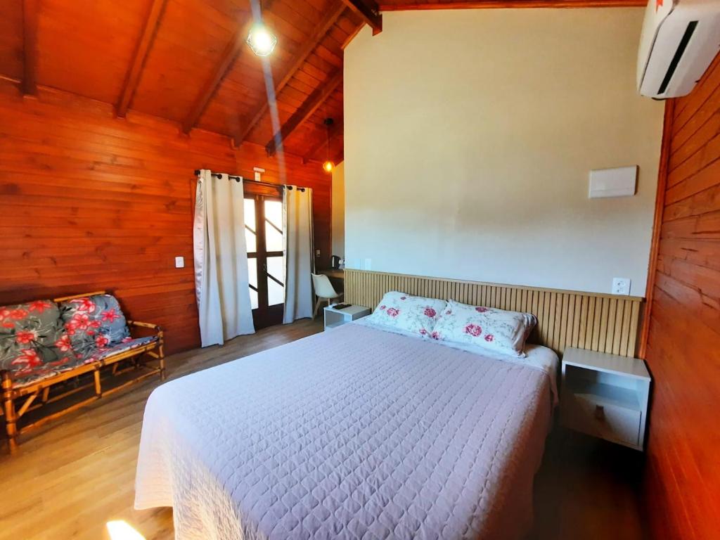 a bedroom with a white bed in a wooden room at Pousada Morada dos Sonhos in Urubici