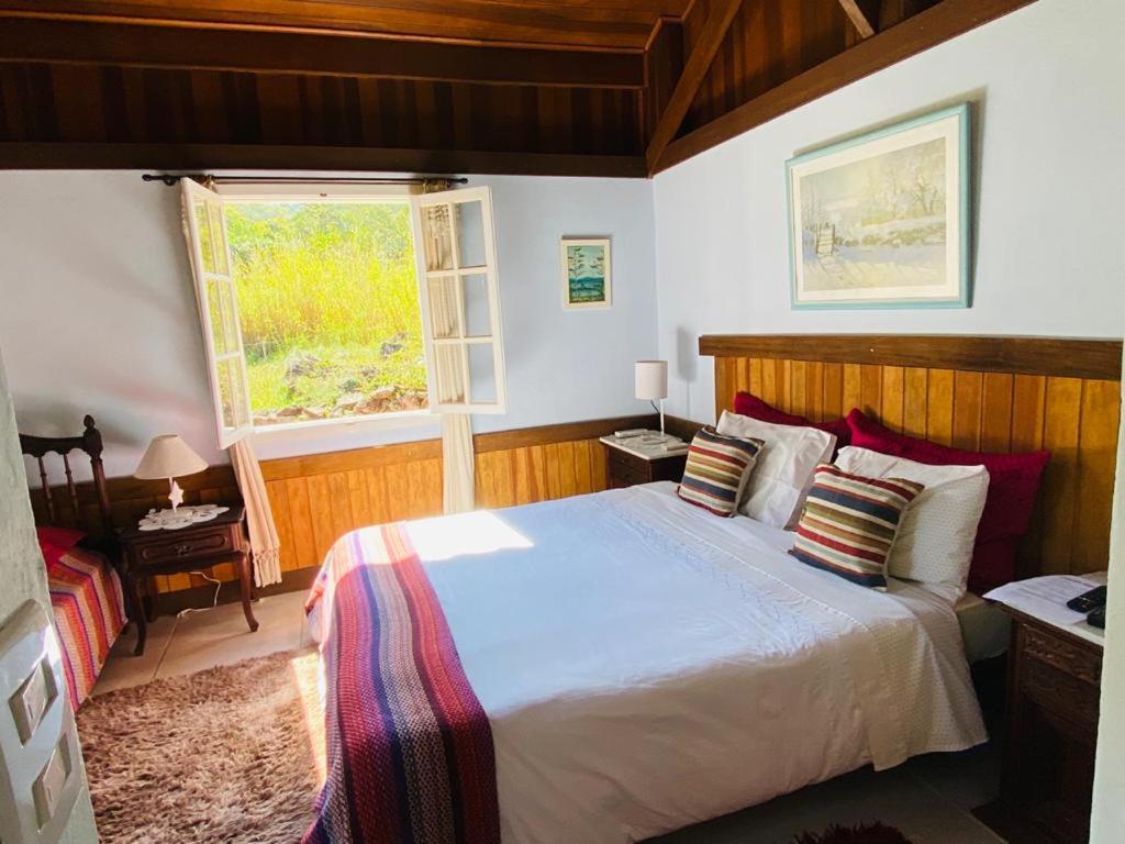Un dormitorio con una cama grande y una ventana. en Pousada Sítio da Luzia, en Engenheiro Passos