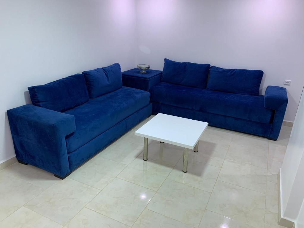 Appart de proximité à bayo في بركان: أريكة زرقاء وطاولة في غرفة المعيشة