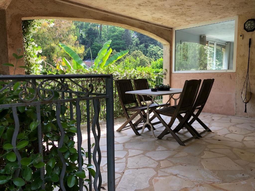 patio con mesa, sillas y ventana en Charmant appartement en rez de villa à Vence, en Vence