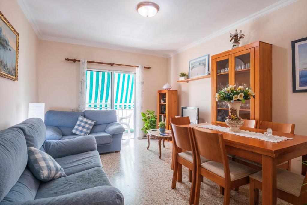a living room with a table and a blue couch at Piso cerca del mar en Alcalá in Alcalá