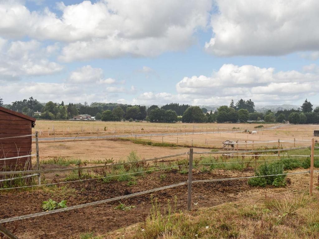 una granja con una valla y un campo con caballos en South Wing Coldharbour Park Farm, en Rake