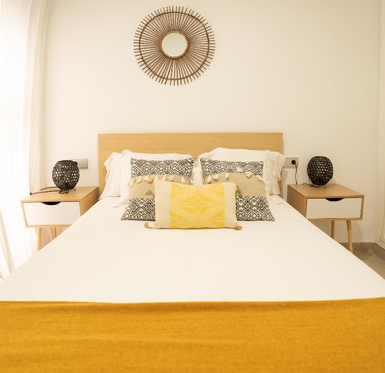 una camera da letto con un grande letto bianco con cuscini di GoToSeville ALTAIR SUITES a Siviglia